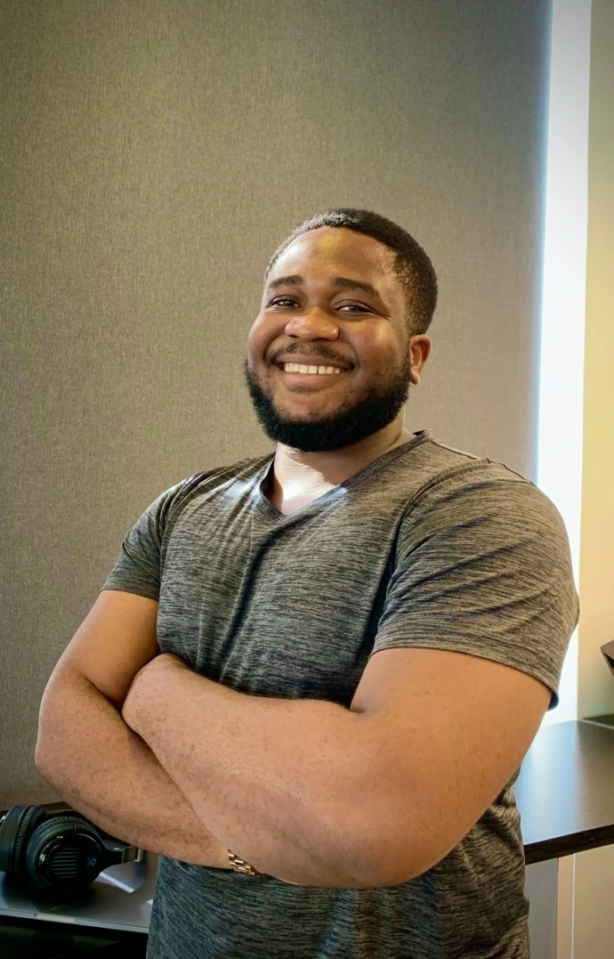 a man with his arms crossed standing in front of a desk